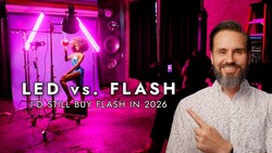 Man in light shirt pointing at studio setup with magenta LED neon lighting and professional flash equipment