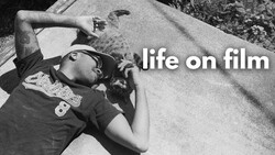 Black and white film photograph of person lying on concrete with text overlay reading 'life on film'