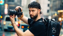 Photographer holding DSLR camera in urban street setting