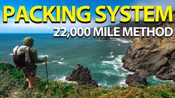 Backpacker with hiking poles standing on coastal cliff overlooking rocky ocean landscape
