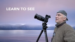 Photographer with telephoto lens on tripod overlooking misty lake landscape at dawn