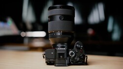 Mirrorless camera with telephoto zoom lens mounted on wooden surface with blurred interior background