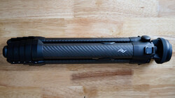 Black carbon fiber camera lens or telephoto zoom with tactical rail and focus ring on wooden surface