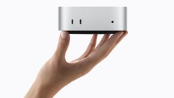 Hand holding a compact silver Mac mini computer