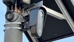 Street-mounted solar security camera and light fixture on concrete pole against clear sky
