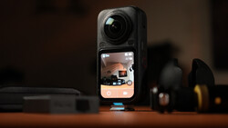Insta360 ONE RS action camera displayed on wooden surface with accessories