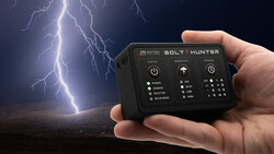 Hand holding a Bolt Hunter storm chasing device with lightning striking in the background