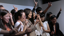 Group of women raising their hands and cheering together at an indoor event
