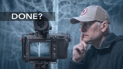 Photographer holding camera with monitor displaying frozen tree, contemplating with hand to chin