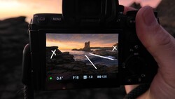 Camera LCD screen displaying coastal sunset composition with exposure settings F16, ISO 125, 0.4s shutter speed