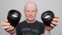 Photographer holding two prime lenses, comparing focal lengths side by side