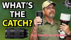 Reviewer holding Sony 100-400mm F/5.6-8 telephoto lens and camera against green background