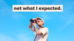 Photographer with camera and sunglasses against blue sky, with text overlay reading 'not what I expected'
