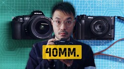 Photographer holding yellow label reading '40MM' with Nikon Z cameras displayed behind him against geometric backdrop
