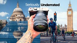 Hand holding vintage rangefinder camera with telephoto lens against London landmarks
