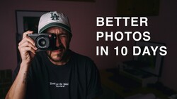 Photographer holding vintage film camera wearing LA Dodgers cap against dark interior backdrop