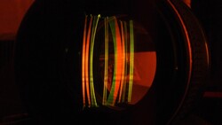 Colorful fiber optic cables glowing inside a dark cylindrical structure with warm red ambient lighting