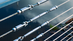 Close-up of stainless steel turnbuckles and tensioned cables on boat rigging