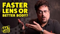 Man with glasses and beard gesturing while discussing camera equipment choice