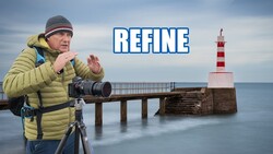 Photographer in yellow jacket with telephoto lens on tripod at seaside lighthouse
