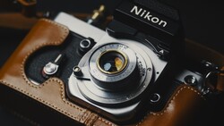 Nikon film camera with brown leather case and vintage lens detail