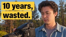 Photographer holding a medium format film camera with a contemplative expression outdoors