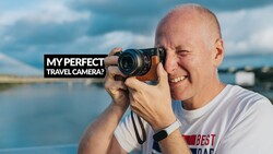 Photographer holding mirrorless camera to eye with water landscape and sky behind