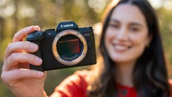 Woman holding Canon EOS mirrorless camera with sensor exposed to camera