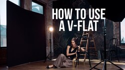 Studio portrait setup with woman seated on ladder beside professional lighting equipment and black v-flat reflector