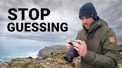 Photographer holding binoculars on a rocky coastal cliff overlooking ocean