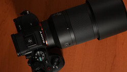 Top-down view of a Sony mirrorless camera with a long Sony lens and large lens hood resting on a reddish-brown wooden table