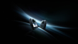Two compact action cameras positioned facing each other against a dramatic dark background with glowing blue light rays