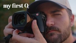 Photographer holding Leica rangefinder camera up to eye while wearing cap