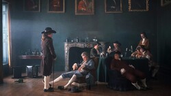 Gentlemen in 18th-century dress lounging and drinking in a dim room with gilt-framed portraits and a marble fireplace.