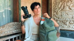 Photographer holding professional DSLR camera and green backpack in ornate interior space