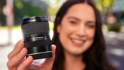 Woman holding a Tamron 18-300mm telephoto zoom lens toward camera