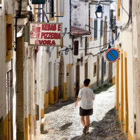 Woman jogging down a narrow cobblestone alley lined with yellow-painted buildings