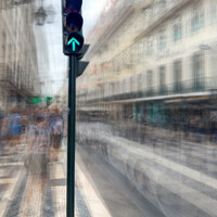 Green traffic light signal on urban street with motion-blurred vehicles and classical Parisian buildings