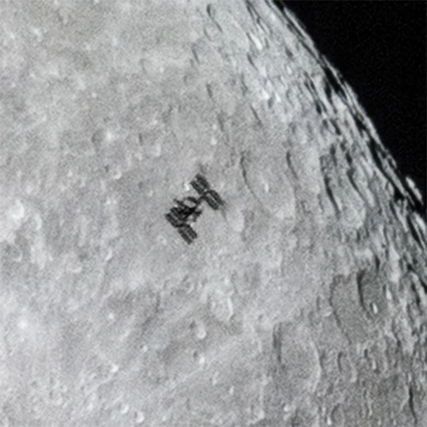 international space station flies in front of moon