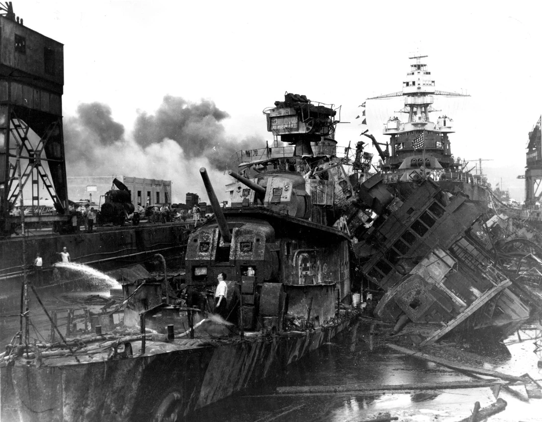 "USS Downes, at left, and USS Cassin, capsized at right, burned out and sunk in the Pearl Harbor Navy Yard drydock on 7 December 1941, after the Japanese attack. The relatively undamaged USS Pennsylvania is in the background." Note the man in a white shir