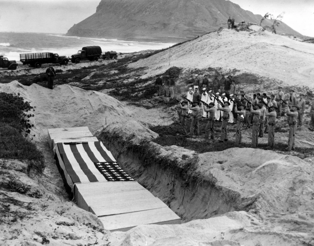 "A Marine rifle squad fires a volley over the bodies of fifteen officers and men killed at Naval Air Station Kaneohe Bay during the Pearl Harbor raid. These burial ceremonies took place on 8 December 1941, the day after the attack."