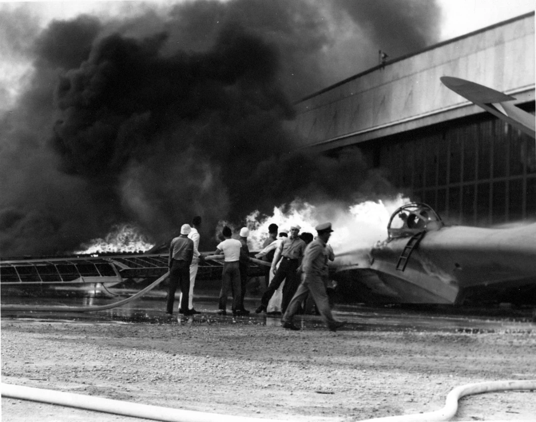 A patrol bomber burning at Naval Air Station Kaneohe, on Oahu, with crews trying to put out the fires.