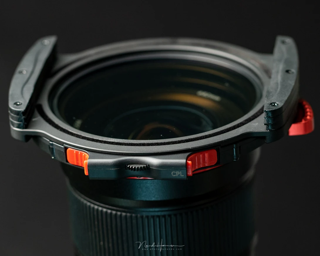 Wide-angle lens with orange and red mechanical elements visible on the barrel and focus ring assembly.