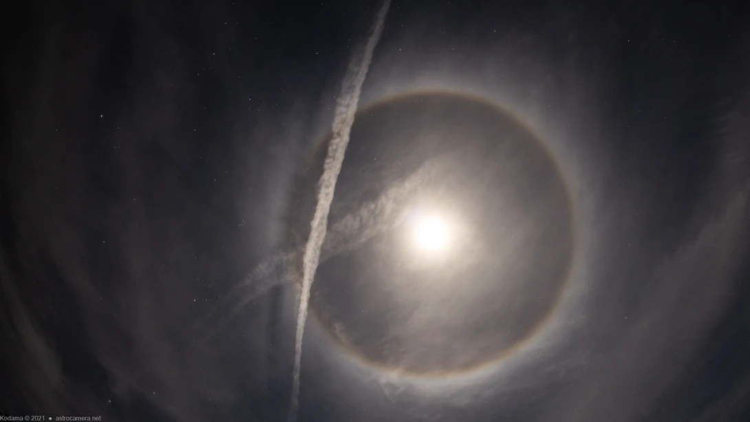 Bright celestial body surrounded by concentric halos and wispy atmospheric rings against a dark starry sky.