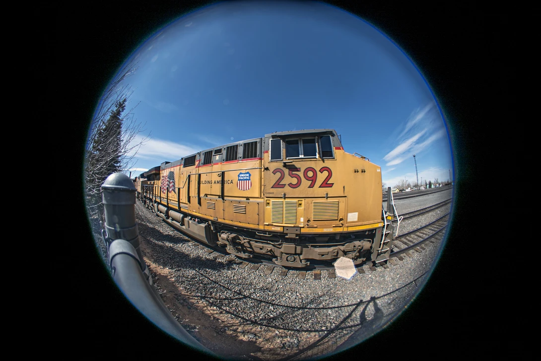 Yellow Union Pacific locomotive numbered 2592 photographed through a fisheye lens on railroad tracks.