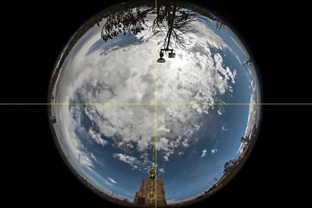 Fisheye view of Earth from space with satellite equipment and solar panels visible in the foreground.