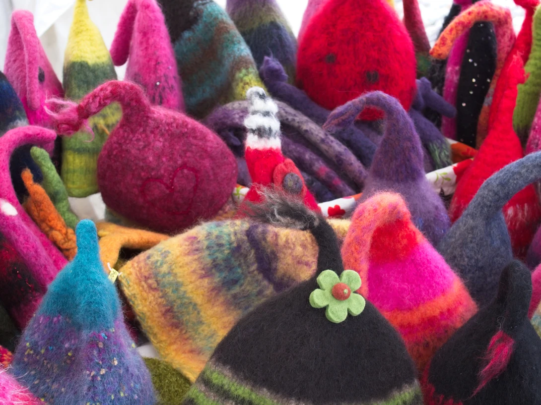 Colorful felted wool gnome figurines with pointed hats in vibrant pink, red, purple, and striped patterns.
