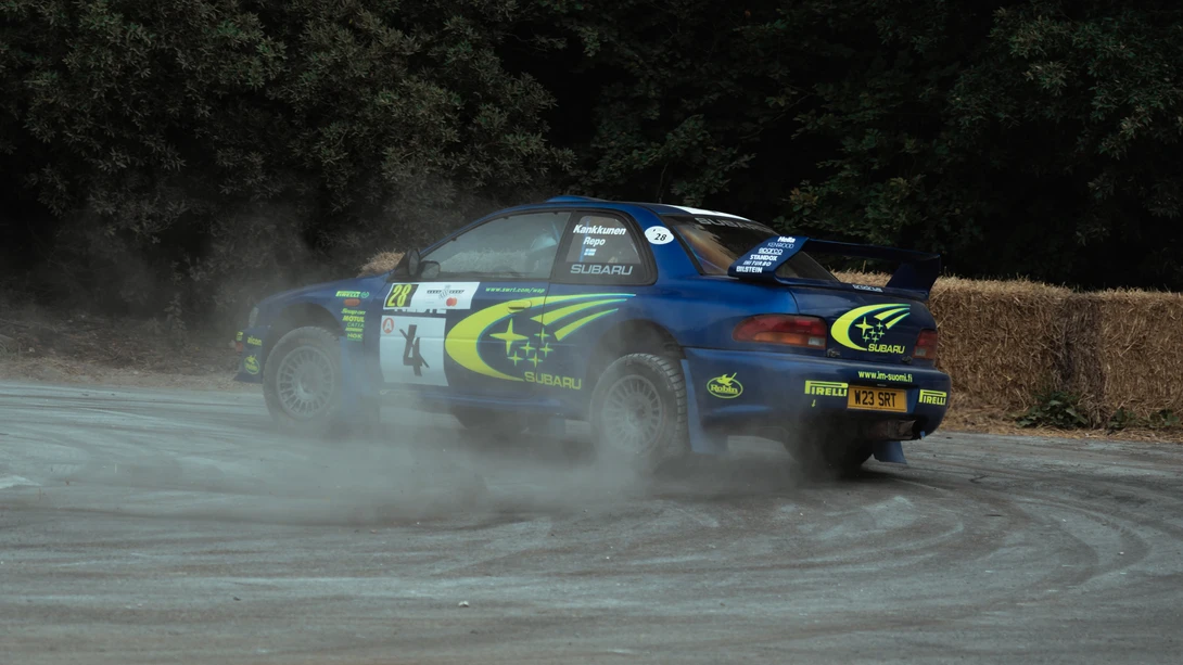 A Subaru World Rally Championship car drifts around a hairpin on the rally stage at Goodwood festival of speed.