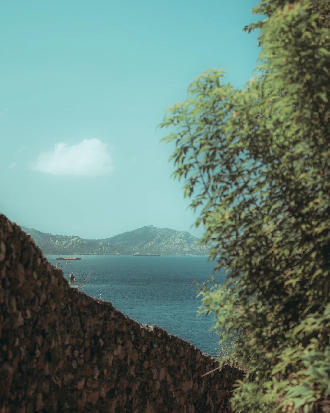 Coastal wall reveals sea view with mountain backdrop