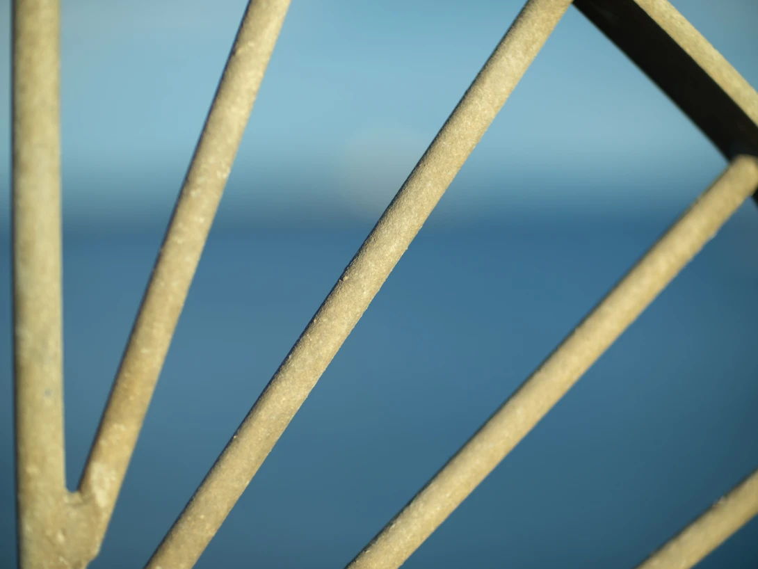 Close-up of weathered wooden structural beams against blue sky and ocean horizon.
